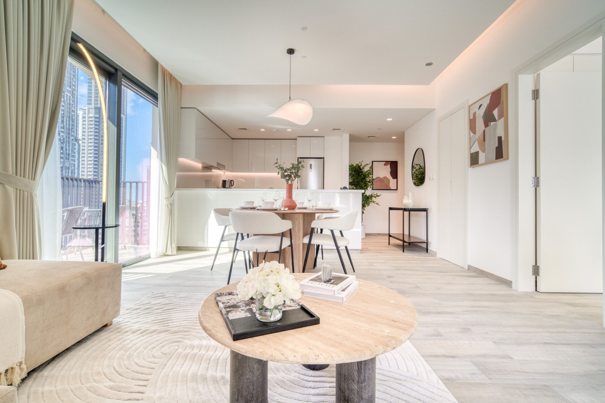 A modern living room with a round coffee table, a sofa, and a dining area with chairs and a table.