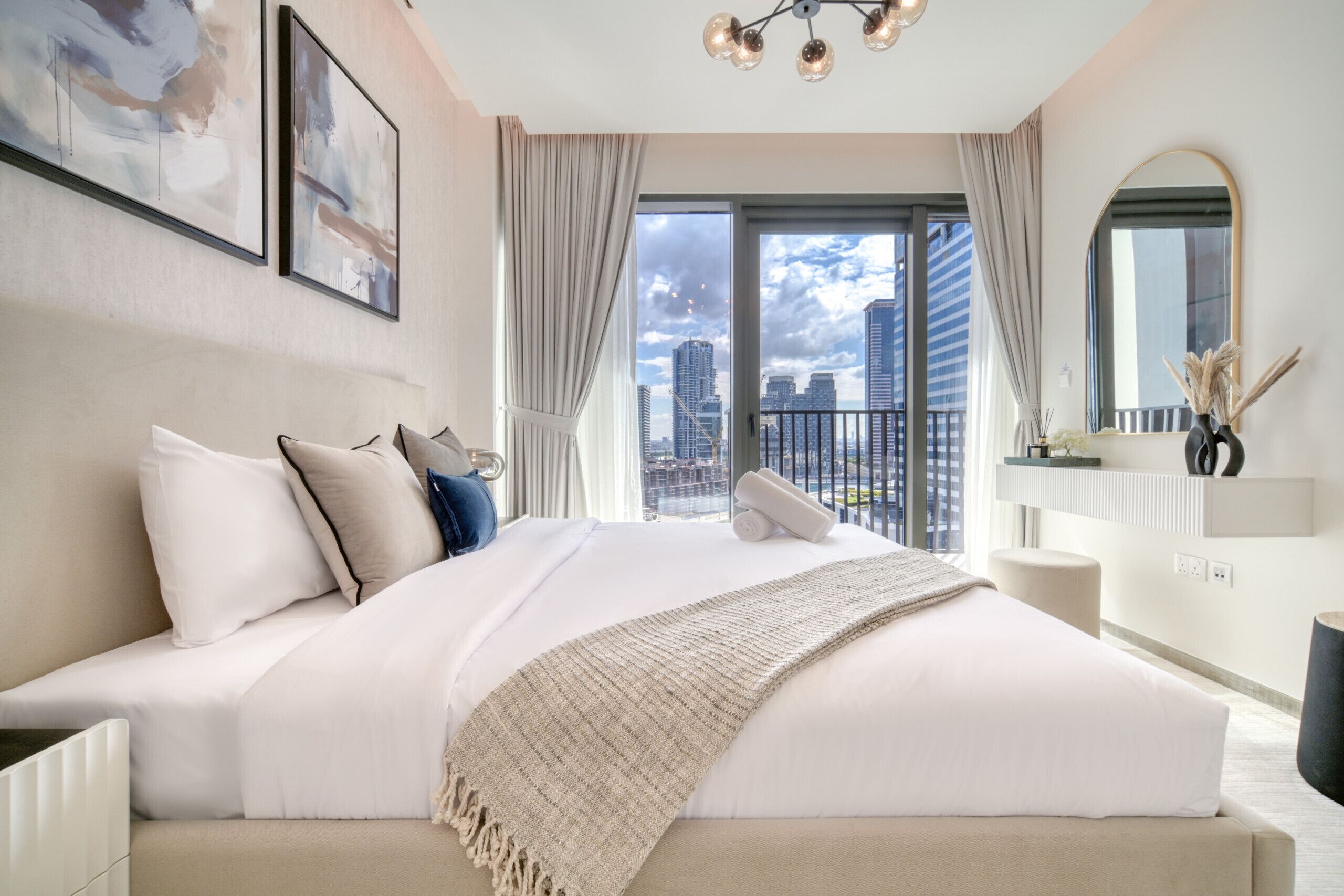 A modern hotel bedroom with a large bed, a city view, and a minimalist decor.