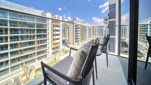 A balcony with modern furniture, a glass railing, and a view of high-rise buildings. - Serene 1BR Apartment in Azizi Riviera 27, Al Merkadh by Deluxe Holiday Homes (Dubai)