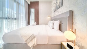 A modern hotel room with a large bed, a bedside table with a lamp, and a view of the city through large windows. - Serene 1BR Apartment in Azizi Riviera 27, Al Merkadh by Deluxe Holiday Homes (Dubai)