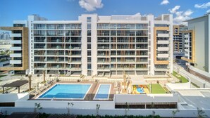 A modern multi-story building with a rooftop pool area, featuring multiple balconies and a landscaped courtyard. - Serene 1BR Apartment in Azizi Riviera 27, Al Merkadh by Deluxe Holiday Homes (Dubai)
