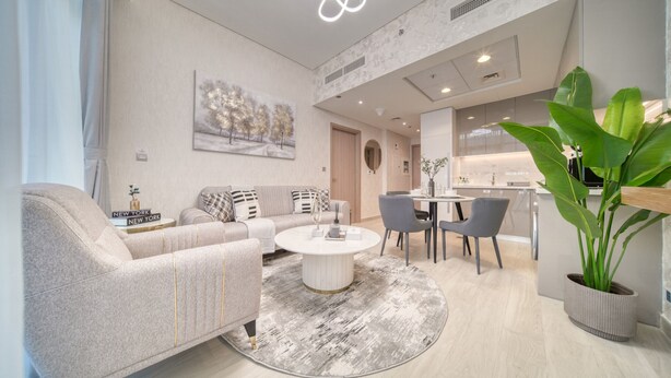 A modern living room with a sofa, coffee table, and dining area. - Serene 1BR Apartment in Azizi Riviera 27, Al Merkadh by Deluxe Holiday Homes (Dubai)