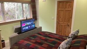 A bedroom with a bed, a television on a stand, a window, and a door. - Taigh Sealladh Fèidh B&B (Invergarry)