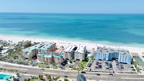 Un hôtel situé sur la côte, composé de plusieurs bâtiments, avec un parking et une plage en arrière-plan.