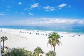 Ein Strand mit weißem Sand, klarem, blauem Wasser und einigen Palmen.