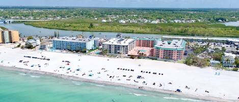 Ein Hotel an der Küste mit mehreren Gebäuden, einem Strand mit Sonnenschirmen und einem Fluss im Hintergrund.