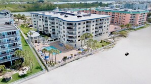 Un hôtel à plusieurs étages doté d’une piscine sur le toit, entouré de palmiers et donnant sur une plage.