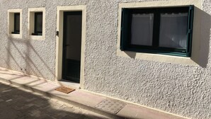 A building facade with textured white walls, three windows with black frames, and a door.