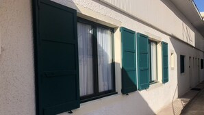 A building with a white exterior and green shutters on the windows.