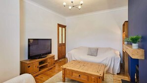 A living room with a television, sofa, coffee table, and wooden cabinet. - Host & Stay | Fifth Avenue (York)