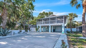 A two-story house with a covered porch, surrounded by palm trees and a well-maintained garden. - 🏠Private Home🌴Relax on the Rocks🐬2 Blocks from Beach🌞Fire Pit and Hot Tub (Indian Rocks Beach)
