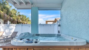 A hot tub with a wooden base, surrounded by a white fence, and a clear view of palm trees and a house in the background. - 🏠Private Home🌴Relax on the Rocks🐬2 Blocks from Beach🌞Fire Pit and Hot Tub (Indian Rocks Beach)