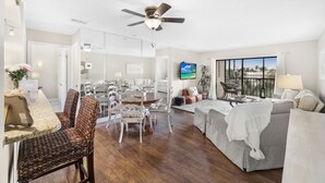 A spacious living area with a dining table, chairs, a sofa, and a ceiling fan. - Central Condo | Pool & Short Walk to Restaurants (Marco Island)