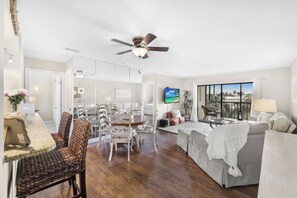A spacious living area with a dining set, a sofa, and a TV mounted on the wall.