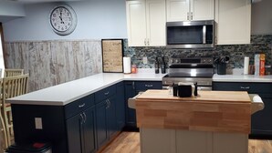 A modern kitchen with dark cabinets, a stainless steel refrigerator, a microwave, and a wooden island. - Hide-a-way at Swan Lake: fishing, relaxing, and dog friendly. (Allegan)