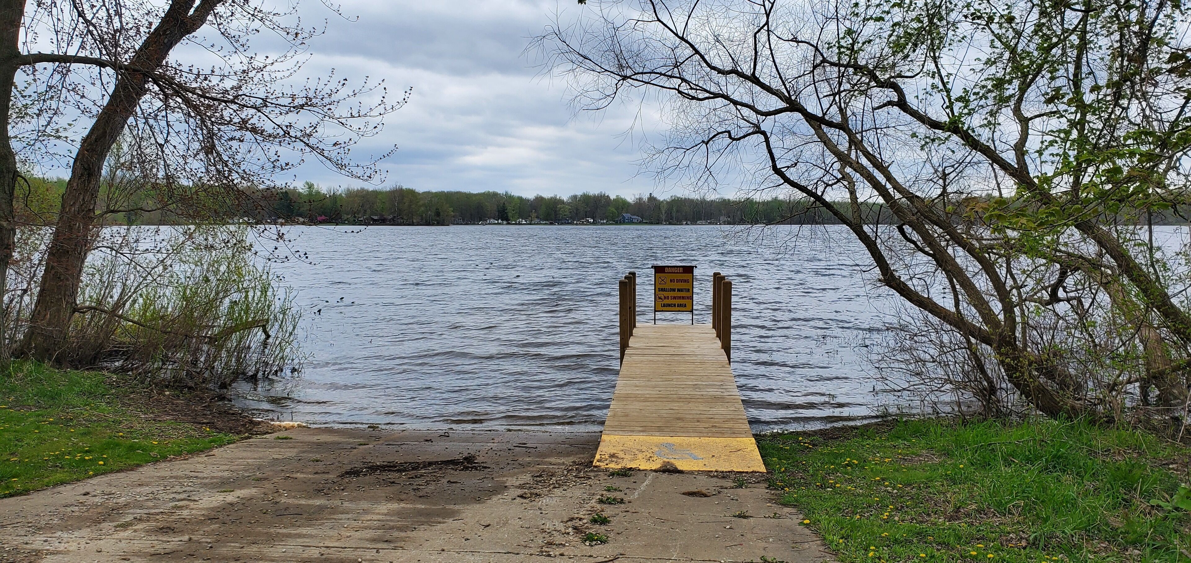 Une jetée en bois qui mène à un lac entouré d’arbres.