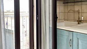 A kitchen with light blue cabinets, a white countertop, and a brass faucet. - Terracielo in the heart of the historic center, suitable for couples, great location (Monopoli)