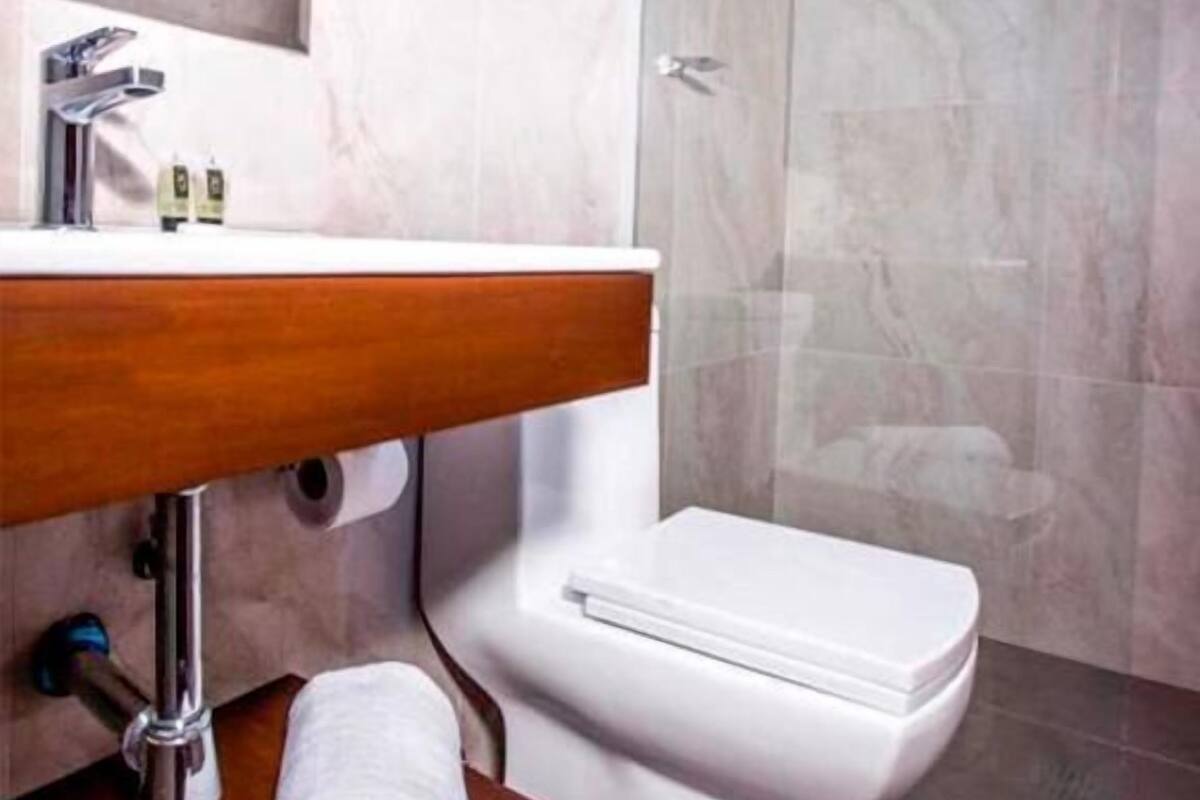 Een moderne badkamer met een houten wastafelmeubel, een wit toilet en een douchecabine met glazen wanden.
