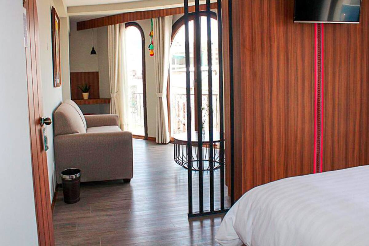 Een hotelkamer met een bed, een sofa, een televisie en een balkon met gordijnen.