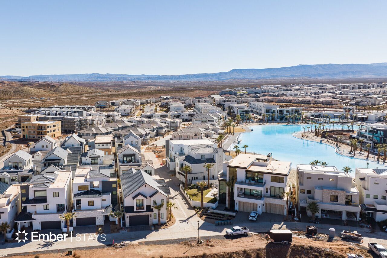 A residential area with modern houses, a swimming pool, and a mountainous backdrop.