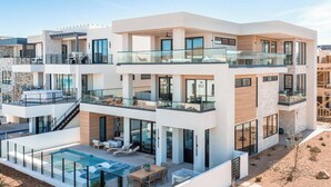 A modern multi-story residential building with a pool, outdoor seating, and balconies. - Desert Sapphire at Desert Color (by Ember Stays) (St. George)