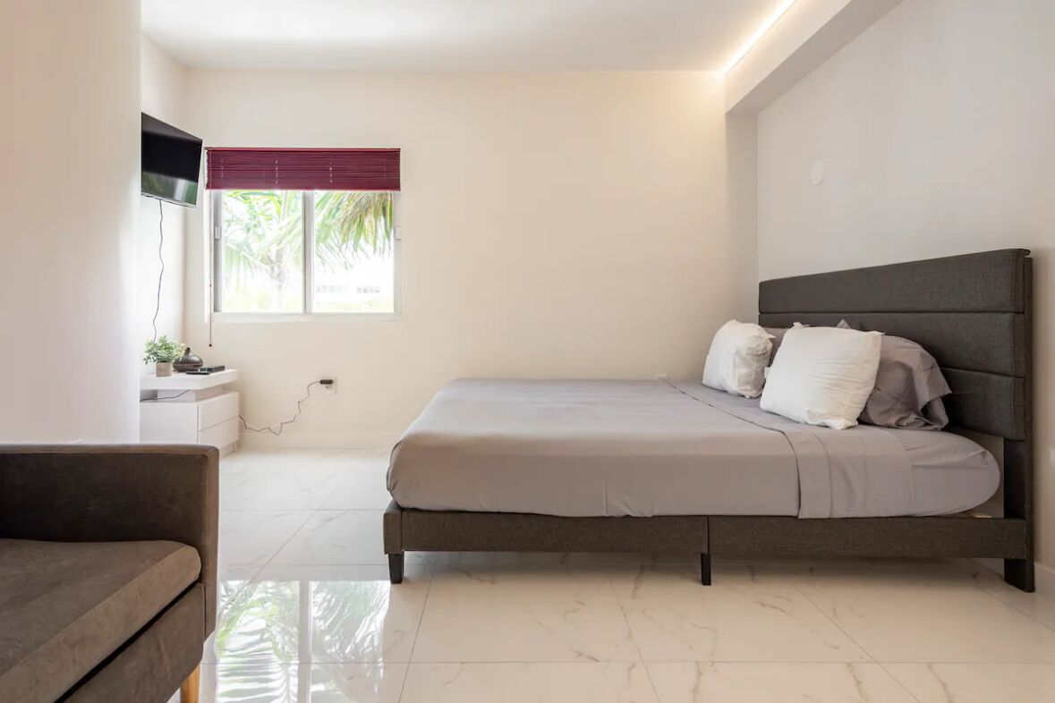 A modern bedroom with a bed, bedside table, and a TV mounted on the wall.