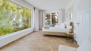 A spacious bedroom with a large window, a bed, a bedside table, and a lamp. - Bienvenido in der Villa Los Pinos (Velilla-Taramay)