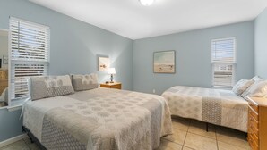 Een slaapkamer met twee bedden, een nachtkastje, een lamp en een schilderij aan de muur.