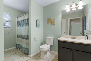 Ein Badezimmer mit Duschvorhang, Toilette, Waschbecken und Spiegel.