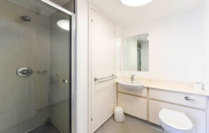 Moderni kylpyhuone, jossa on lasinen suihkuseinä, valkoinen pesuallas ja wc-istuin.