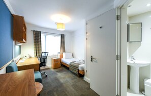 Hotellihuone, jossa on sänky, työpöytä, tuoli sekä kylpyhuone, jossa on pesuallas ja wc.