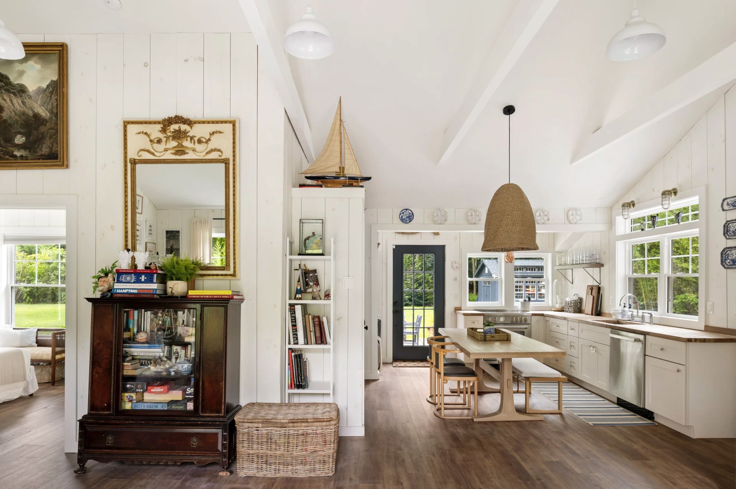 A spacious kitchen with a dining area, wooden flooring, and a large mirror.