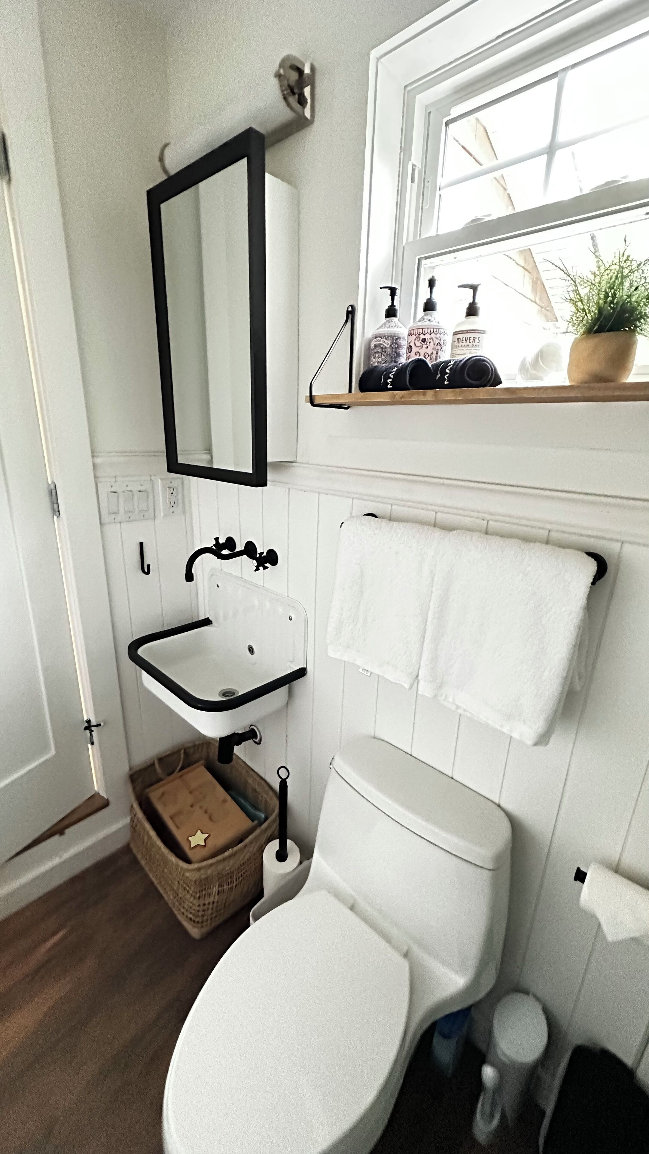 Un baño con un lavamanos blanco, inodoro, espejo y ventana.