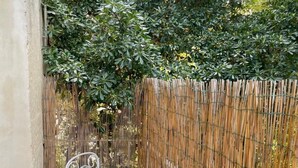 A small outdoor seating area with two metal chairs and a table, enclosed by a bamboo fence. - Charming apartment with garden in Lecce (LECCE)