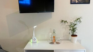 A modern room with a white desk, a mounted TV, a potted plant, and a chair. - Charming apartment with garden in Lecce (LECCE)