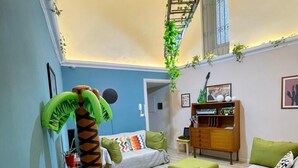 A living room with a sofa, a green armchair, a small table, and a decorative plant. - Charming apartment with garden in Lecce (LECCE)