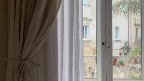 Et værelse med udsigt til bygninger og en balkon.
