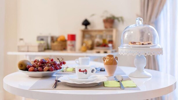 Et morgenbord med en tallerken frugt, en kop med teksten "Quanta", et teko og et overdækket dessertfad.