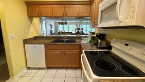 Una cocina con armarios de madera, lavavajillas, estufa y microondas.
