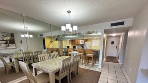 Una cocina moderna con comedor, que incluye una mesa de vidrio grande, sillas de madera y un candelabro.