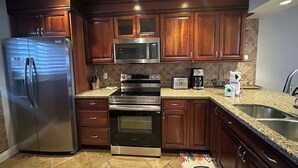 A modern kitchen with stainless steel appliances, wooden cabinets, and granite countertops. - Contemporary Garden View, 2nd Floor (Sarasota)