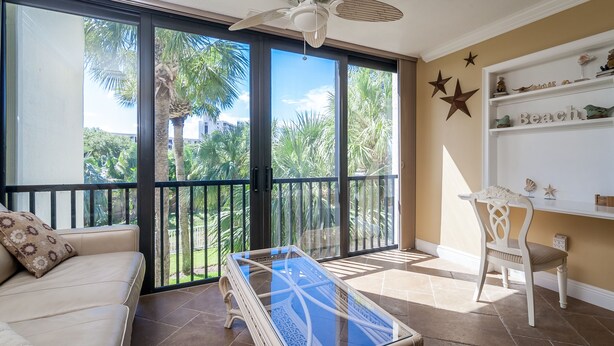 A balcony with a ceiling fan, a glass coffee table, a sofa, and a chair. - Contemporary Garden View, 2nd Floor (Sarasota)