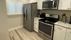 A modern kitchen with stainless steel appliances, white cabinetry, and a patterned rug. - Recently renovated third floor (Sarasota)