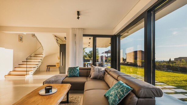 A modern living room with a large sectional sofa, a wooden coffee table, and a staircase leading to an upper level. - Beautiful Villa Angelina in Kastelir (Kastelir)