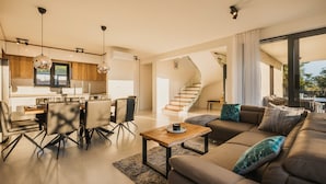 A modern living room with a sofa, coffee table, and dining area. There is a staircase leading to an upper level. - Beautiful Villa Angelina in Kastelir (Kastelir)