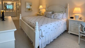 Quarto bem arrumado com uma cama grande, mesas de cabeceira, cômoda e espelho.