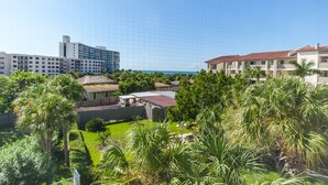 Een resort met meerdere gebouwen, weelderige begroeiing en een helder uitzicht op de oceaan.