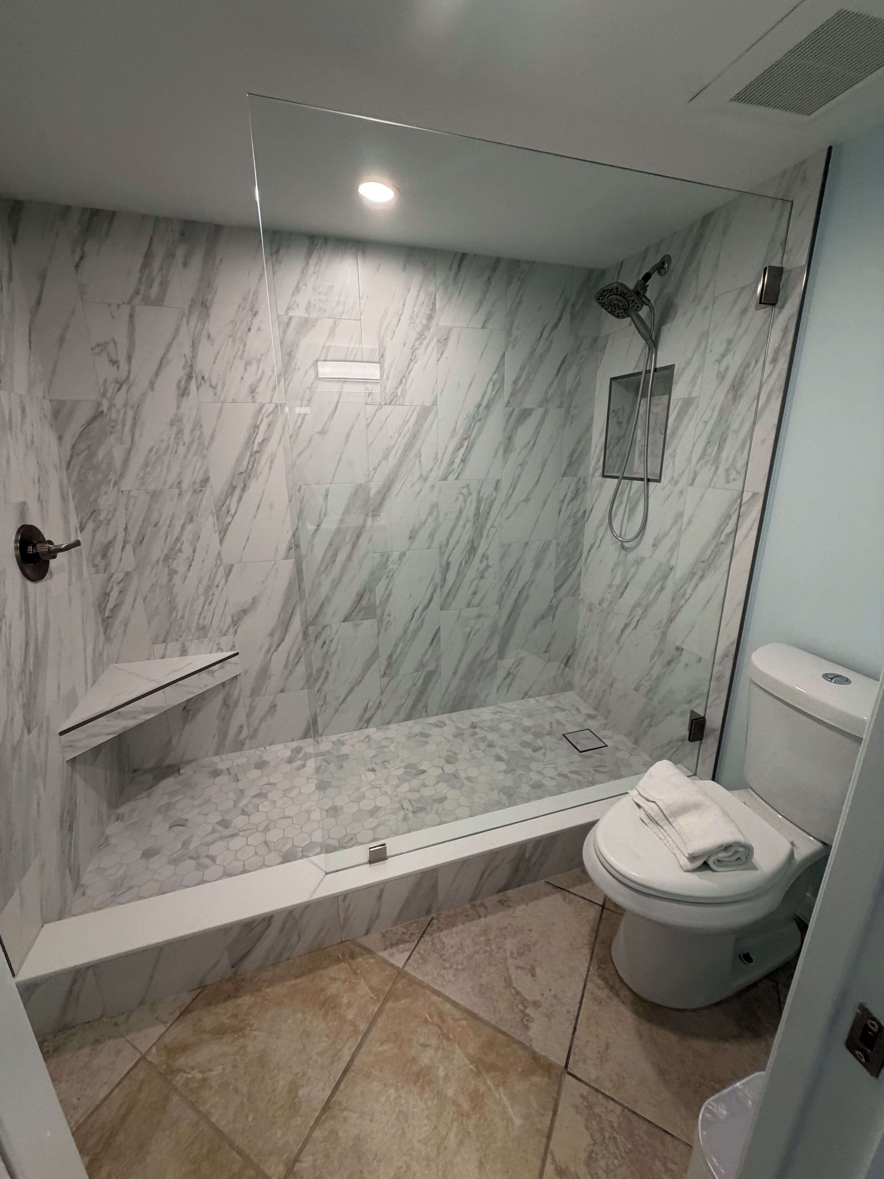A bathroom with a shower, toilet, and marble walls.