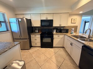 A kitchen with white cabinets, stainless steel appliances, a granite countertop, and a tiled floor. - Bright and spacious 3 bedroom, 4th Floor unit (Sarasota)