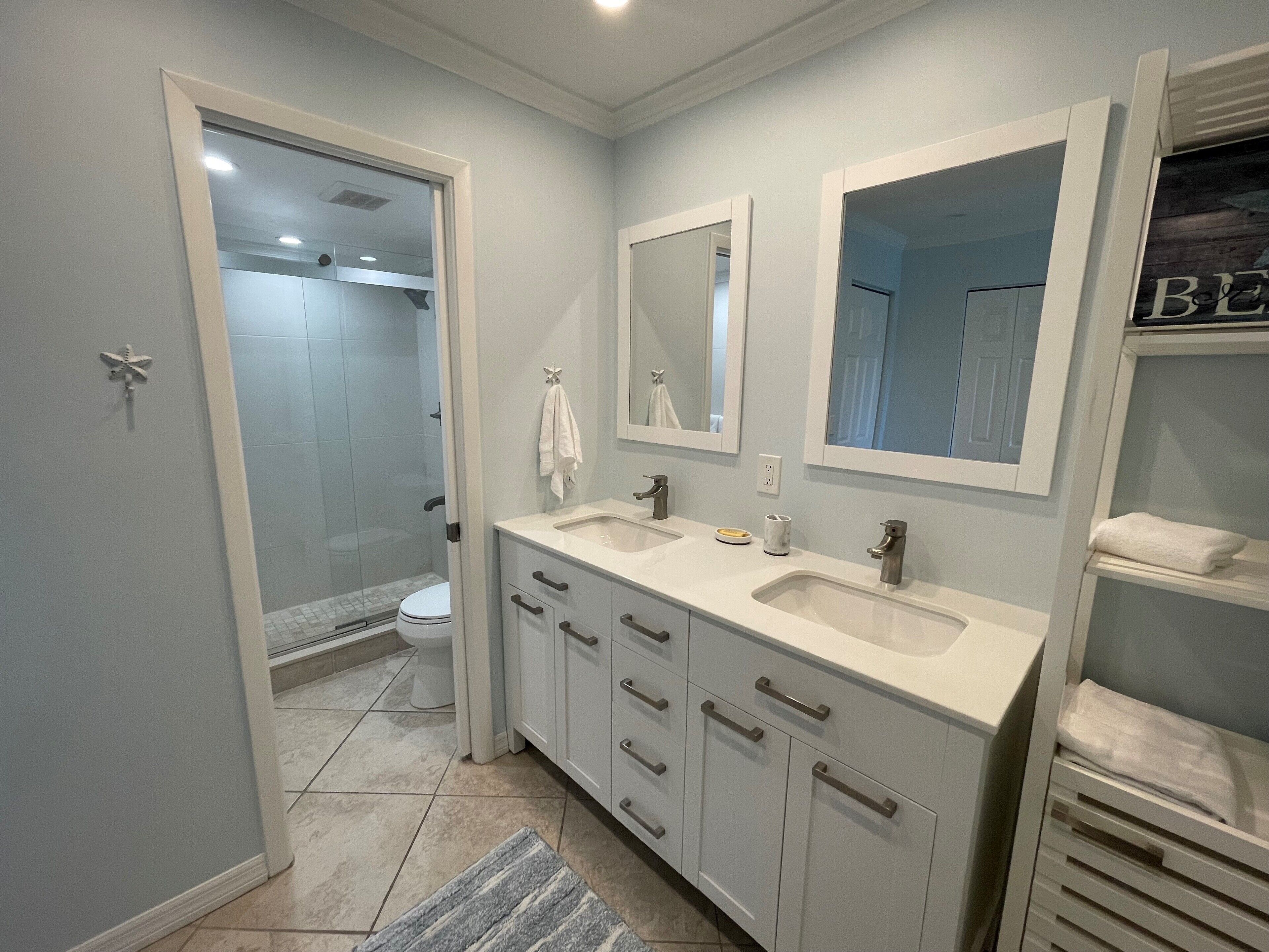 Un baño moderno con dos lavamanos, una ducha y un inodoro.
